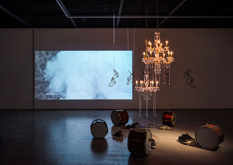 (좌) 좀펫 쿠스위다난토(Jompet KUSWIDANANTO), 〈On Paradise, On Love〉, 2017. 싱글채널 비디오, edition of 5 + 1 artist's proof, 6시간 30분 루프. Ⓒ아라리오갤러리 (우) 좀펫 쿠스위다난토 (Jompet KUSWIDANANTO), 〈On Paradise, The Dogs〉, 2018. 촛대, 드럼, 신발, 마스크, 가변크기. Ⓒ아라리오갤러리