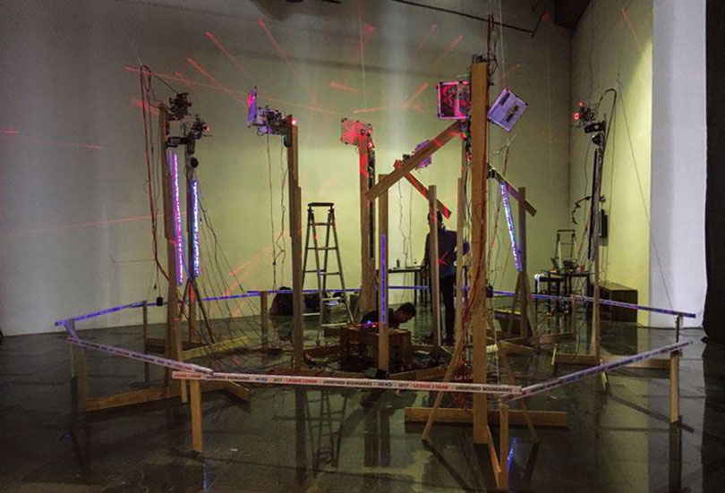 Uudam Tran Nguyen 〈License 2 Draw – Laser Target Shooting〉 Robot, app, electronics, arduino, webcam camera, ip cameras, canvas, color pens, Mac laptop, installation, lasers, paper, fan 설치전경 가변크기 2016